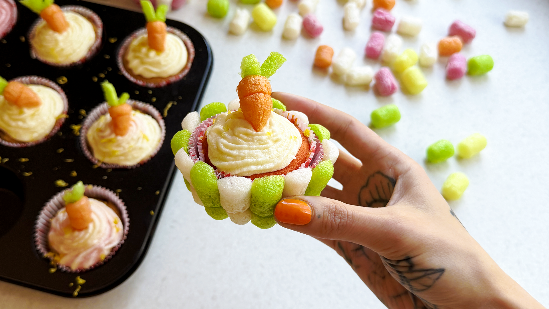 Ein Cupcake mit hellem Frosting und einer Karotte aus Playmais als Deko.