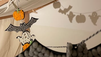 Geister-Kürbis-Fledermaus-Girlande aus Playmais als Deko am Kinderbett.